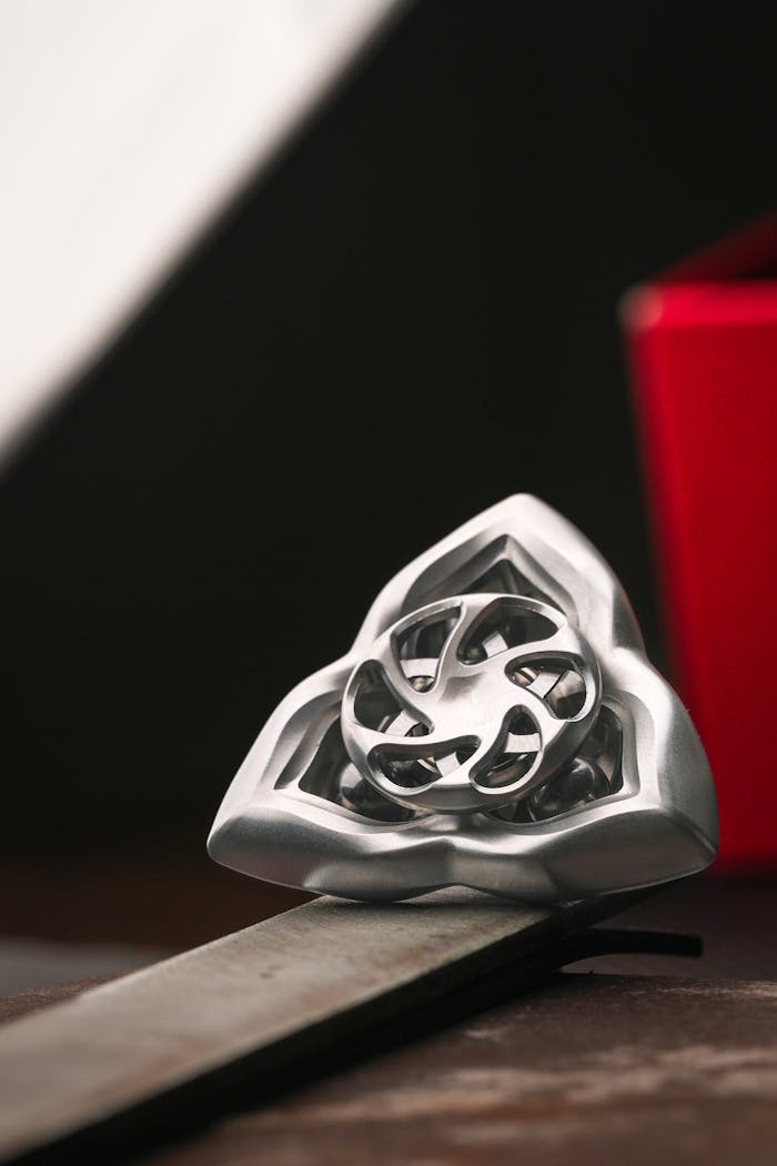 Home Close-up of a silver triquetra-shaped ornament on a red background, elegant and minimalistic.